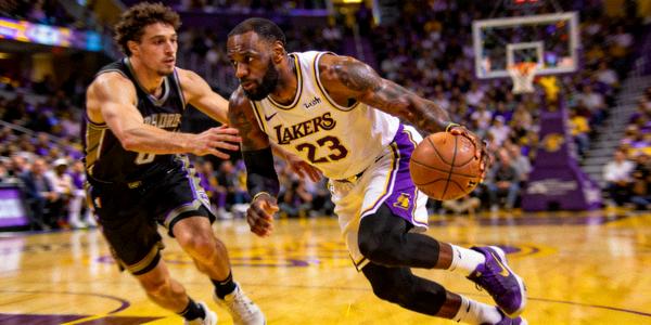 NBA季后赛现场，詹姆斯持球突破防守球员瞬间，球场灯光聚焦